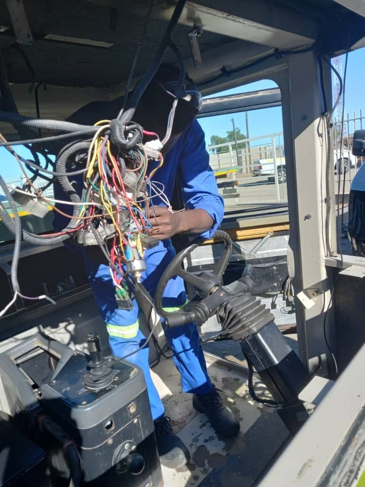 A technician working on wiring inside a vehicle cab